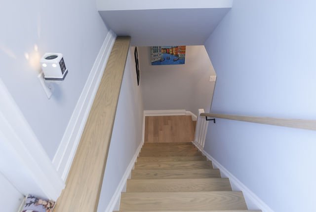 Soca Services applying stain to stairs with white sides for a clean, professional finish