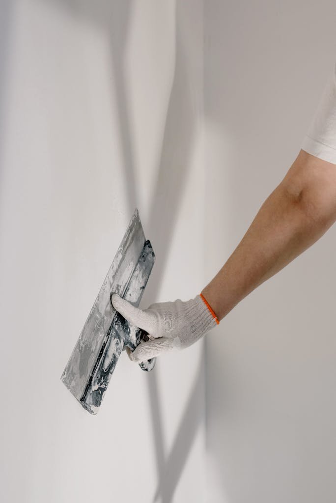 soca services male worker in gloves holding putty knife while working at home in interior painting