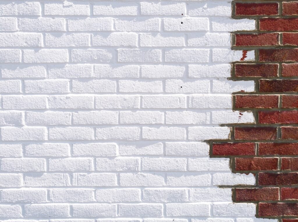 Brick wall showing dramatic contrast between painted white brick and natural red brick