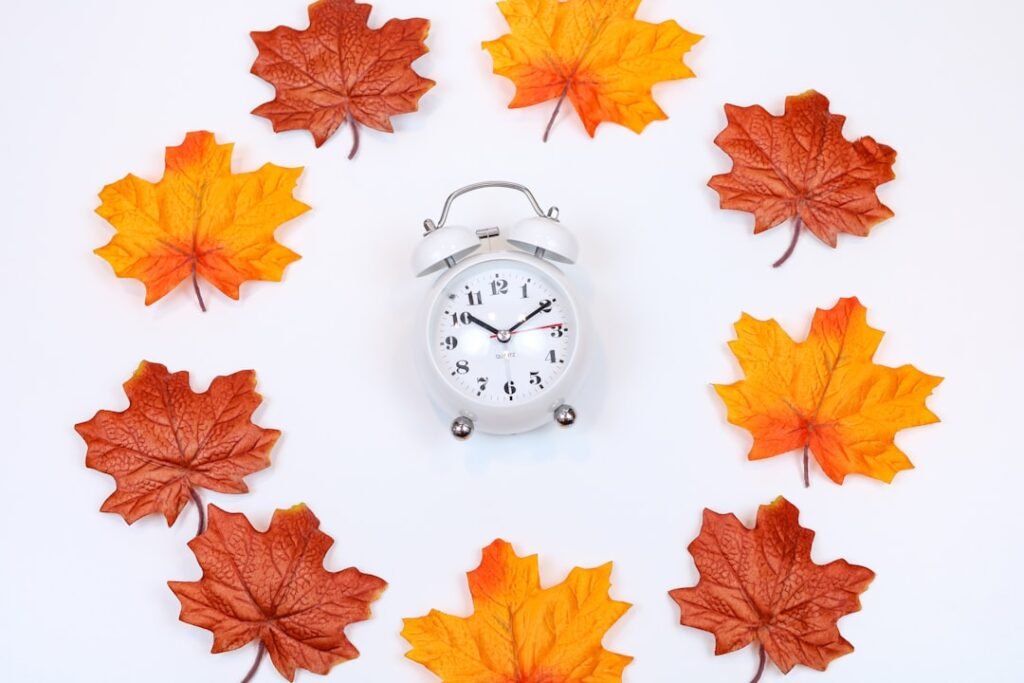 Autumn leaves arranged around a clock representing seasonal timing for exterior painting projects