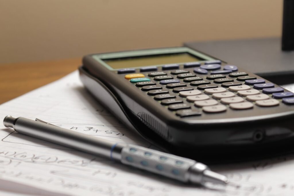 Calculator and pen with written calculations for budgeting popcorn ceiling removal costs in Toronto